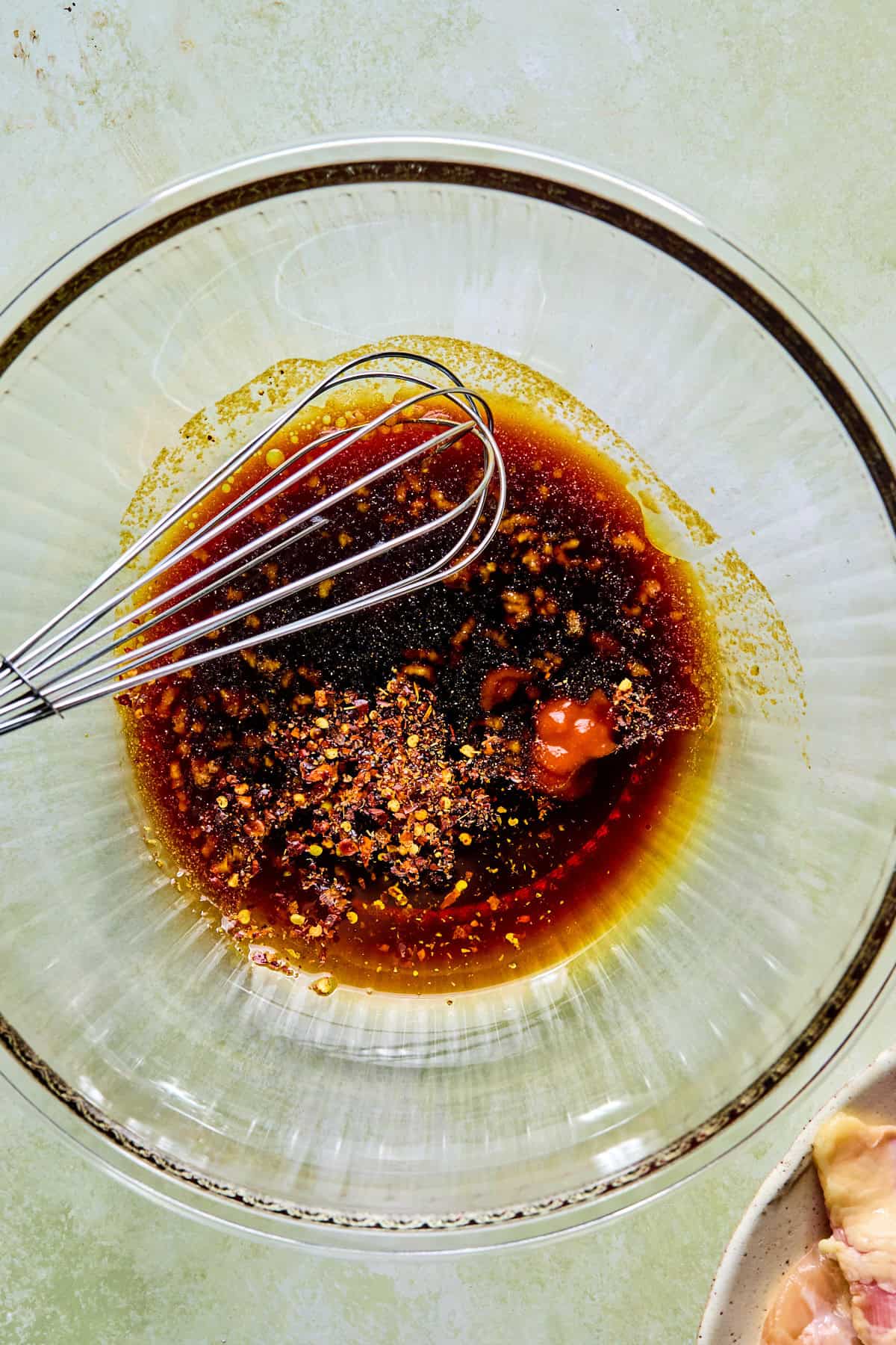 Chicken marinade ingredients in a clear glass bowl, ready to be whisked together.