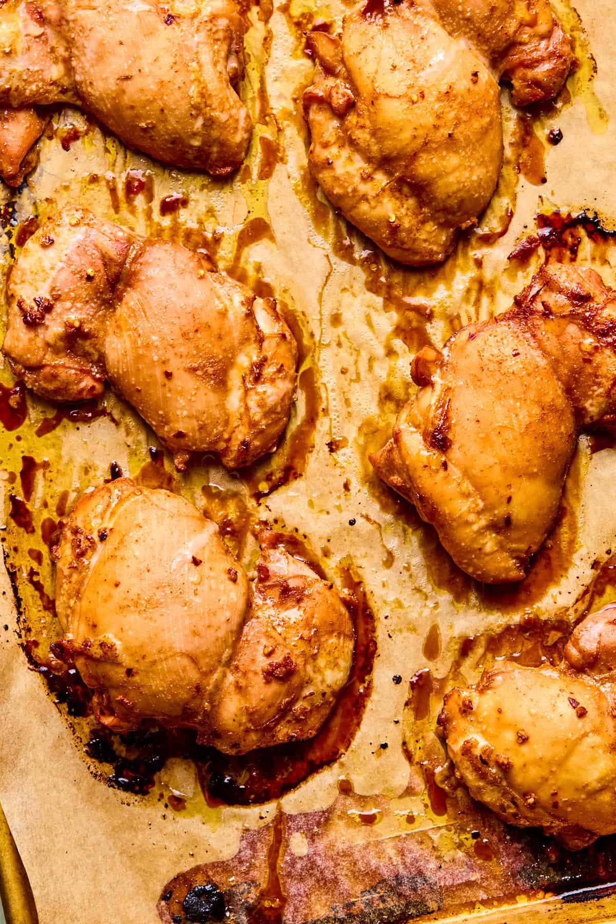 Baked chicken thighs on a parchment-lined baking sheet.