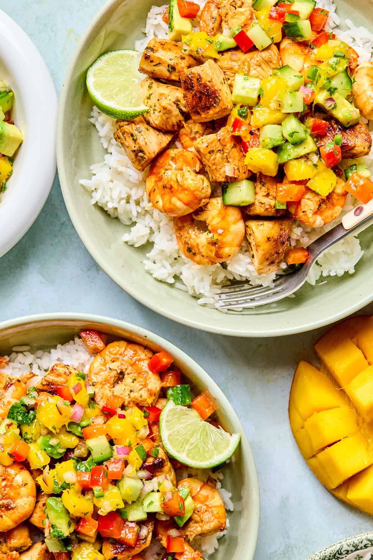 2 bowls of chicken and shrimp over rice with mango salsa