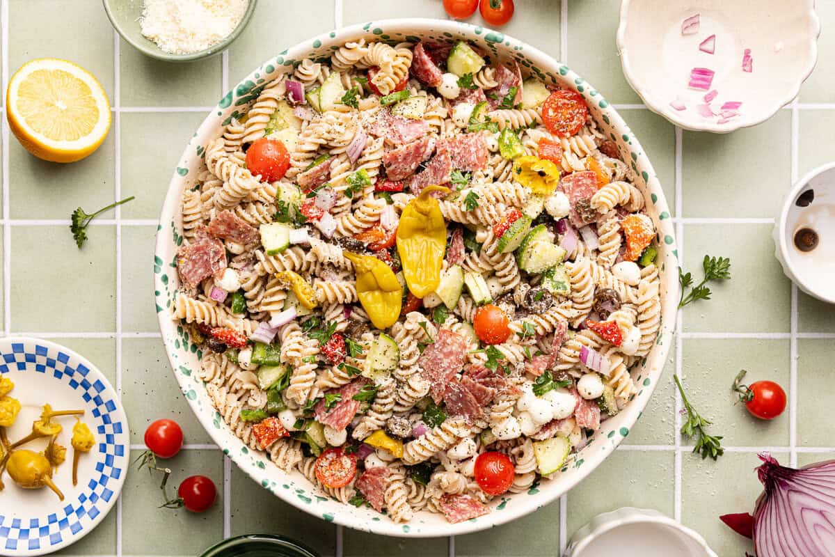 Gluten free pasta salad assembled in a decorative serving bowl and topped with extra pepperoncinis.