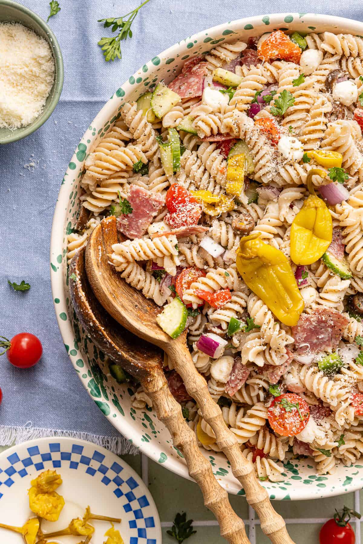Gluten free pasta salad served in a decorative bowl with wooden serving spoons ready for serving.