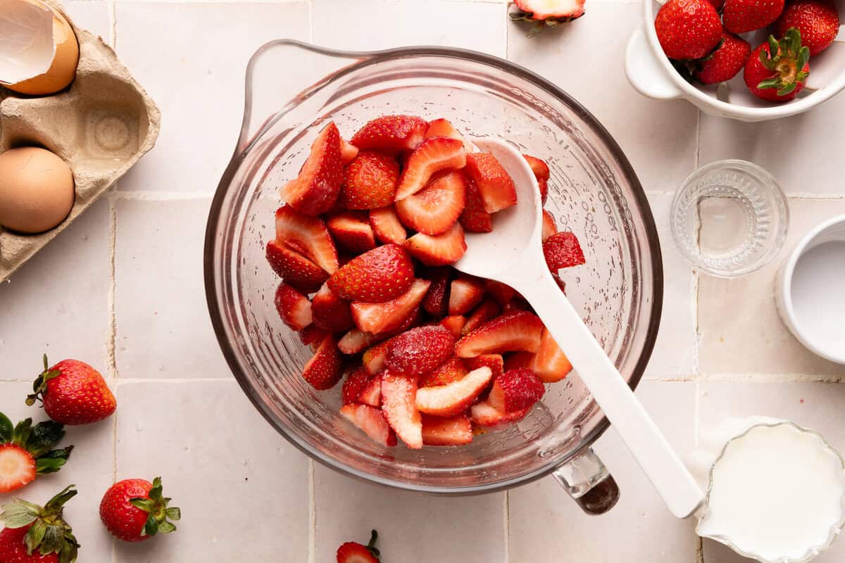 strawberries, sugar, and lemon juice mixed in a glass bowl