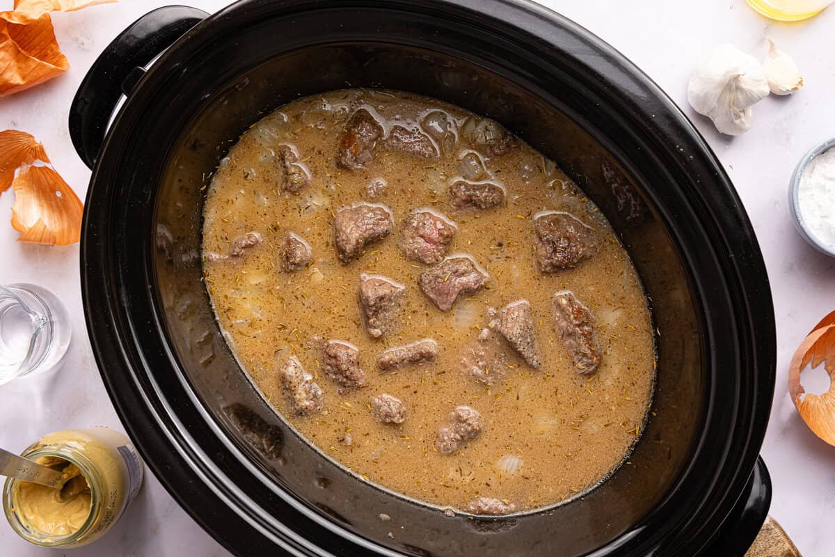 beef tips and gravy uncooked in a slow cooker