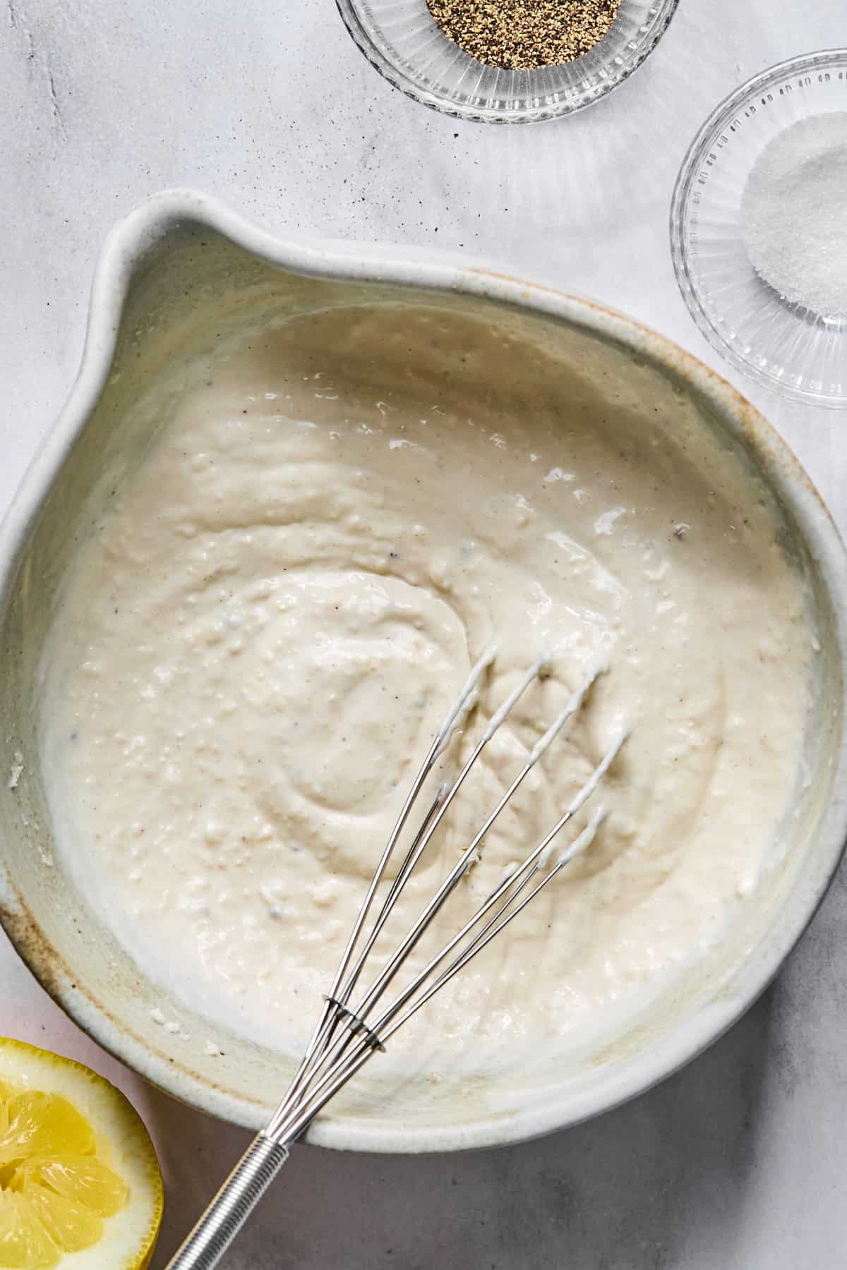 homemade caesar dressing in a bowl with a small whisk
