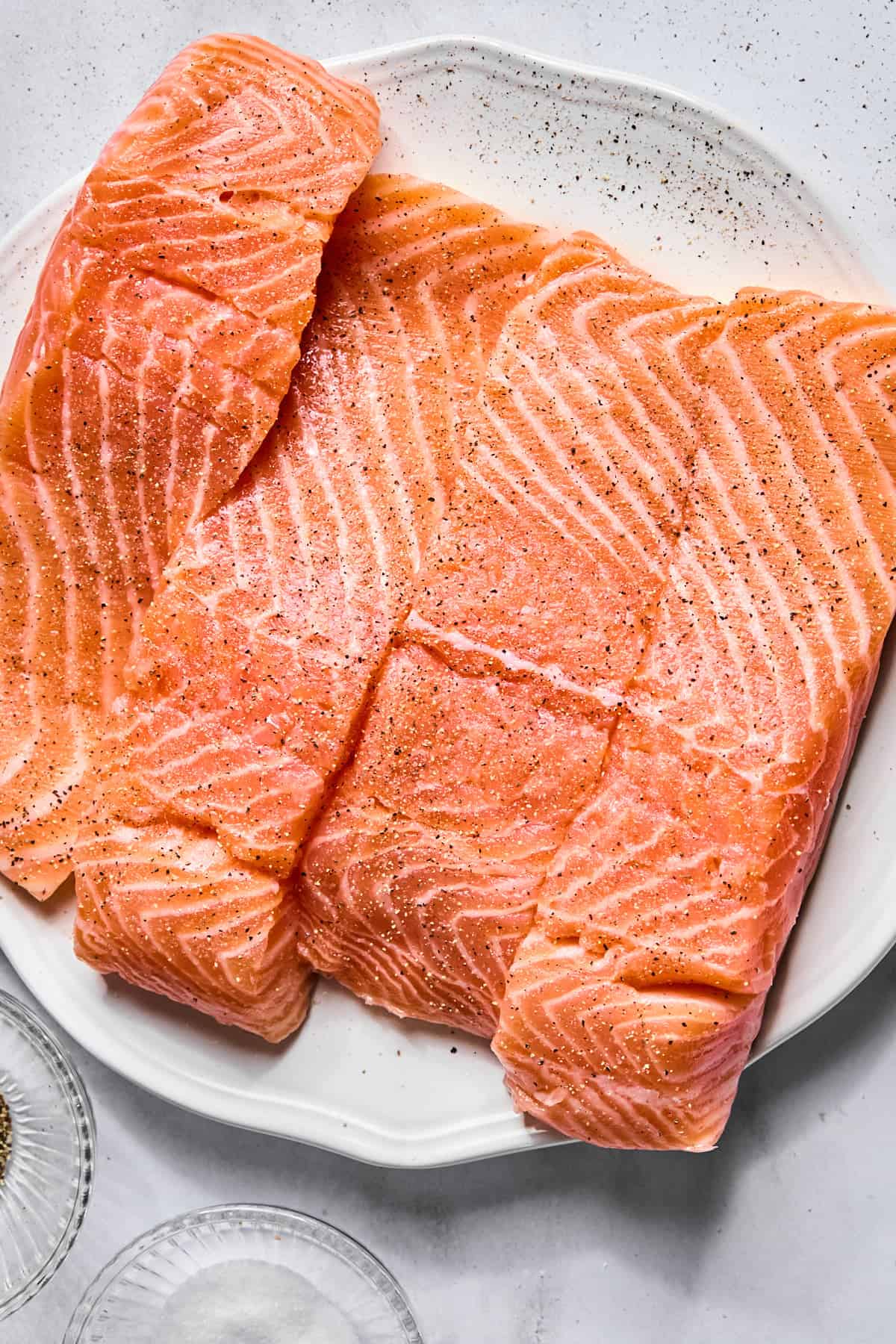 raw salmon fillets on a plate seasoned with salt and pepper