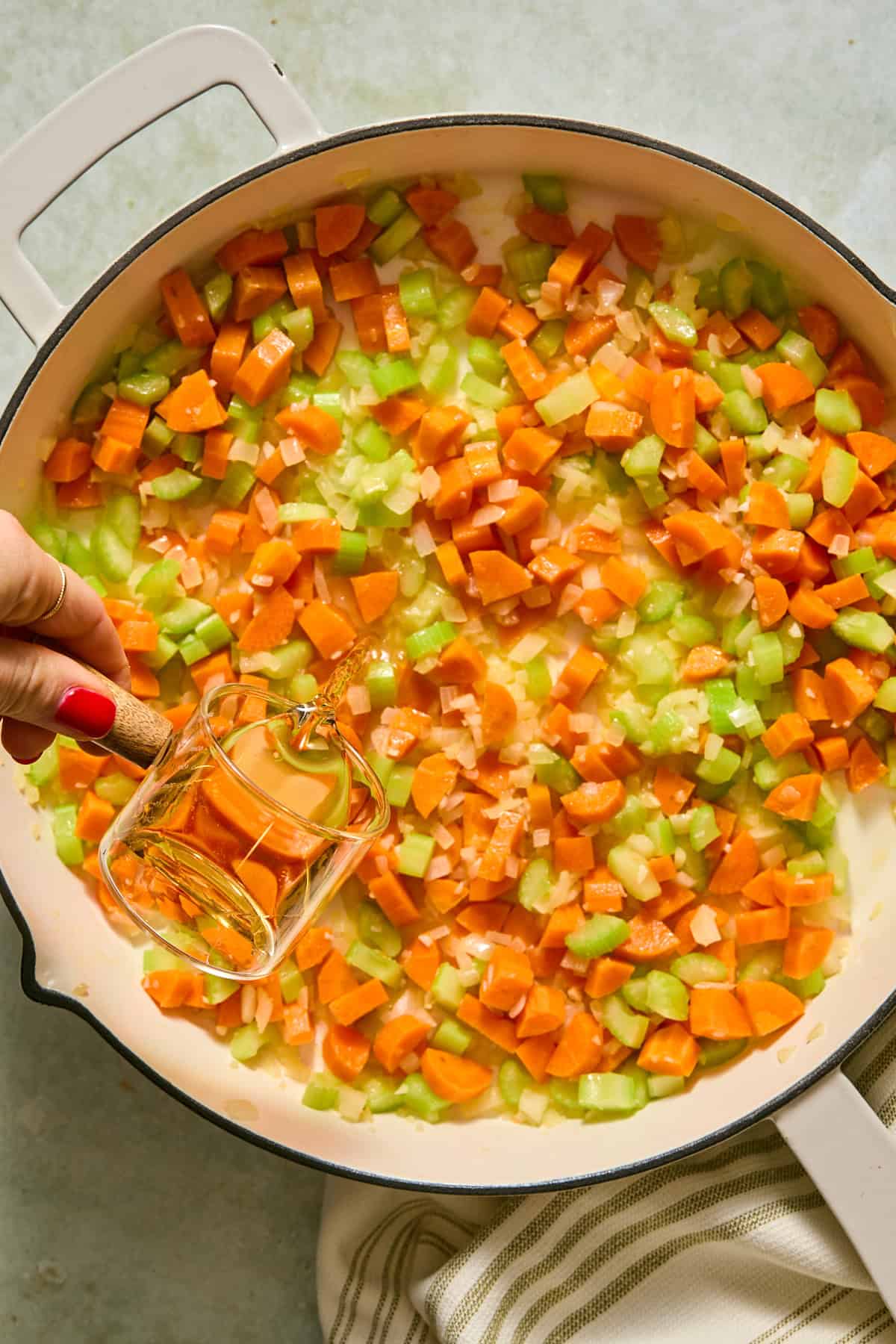 Sherry being added into the large skillet with the melted butter, and softened vegetables.