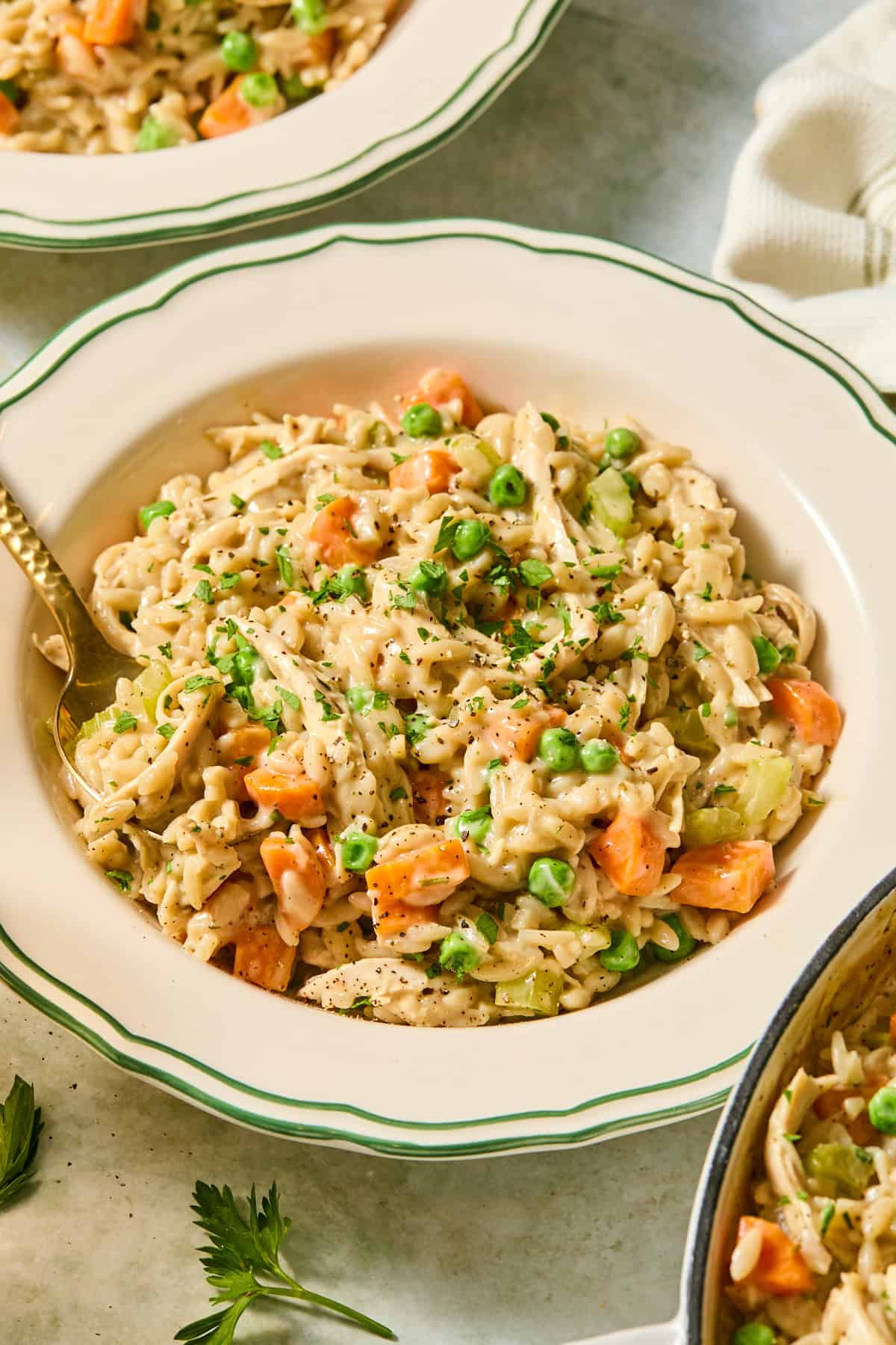 A bowl filled with chicken pot pie orzo garnished with fresh chopped parsley.