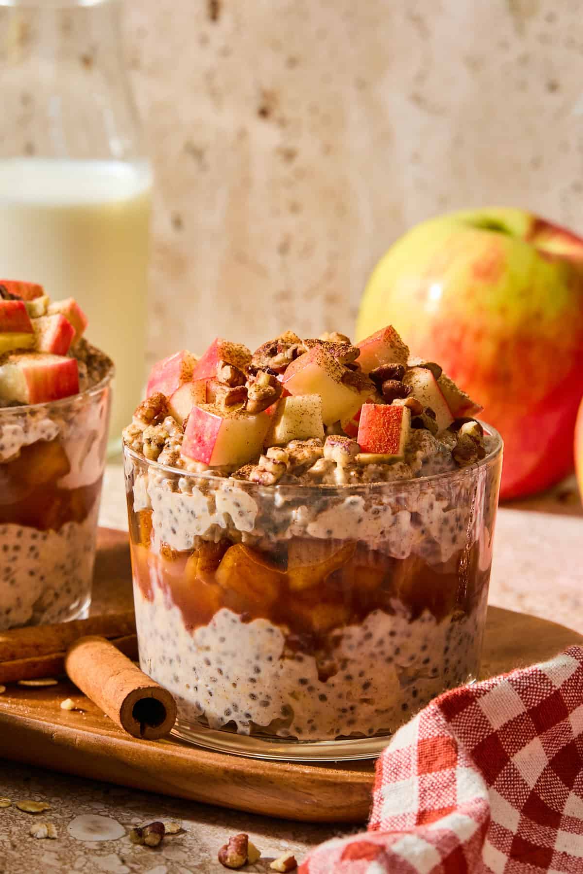 apple pie overnight oats in a glass jar topped with apples and walnuts