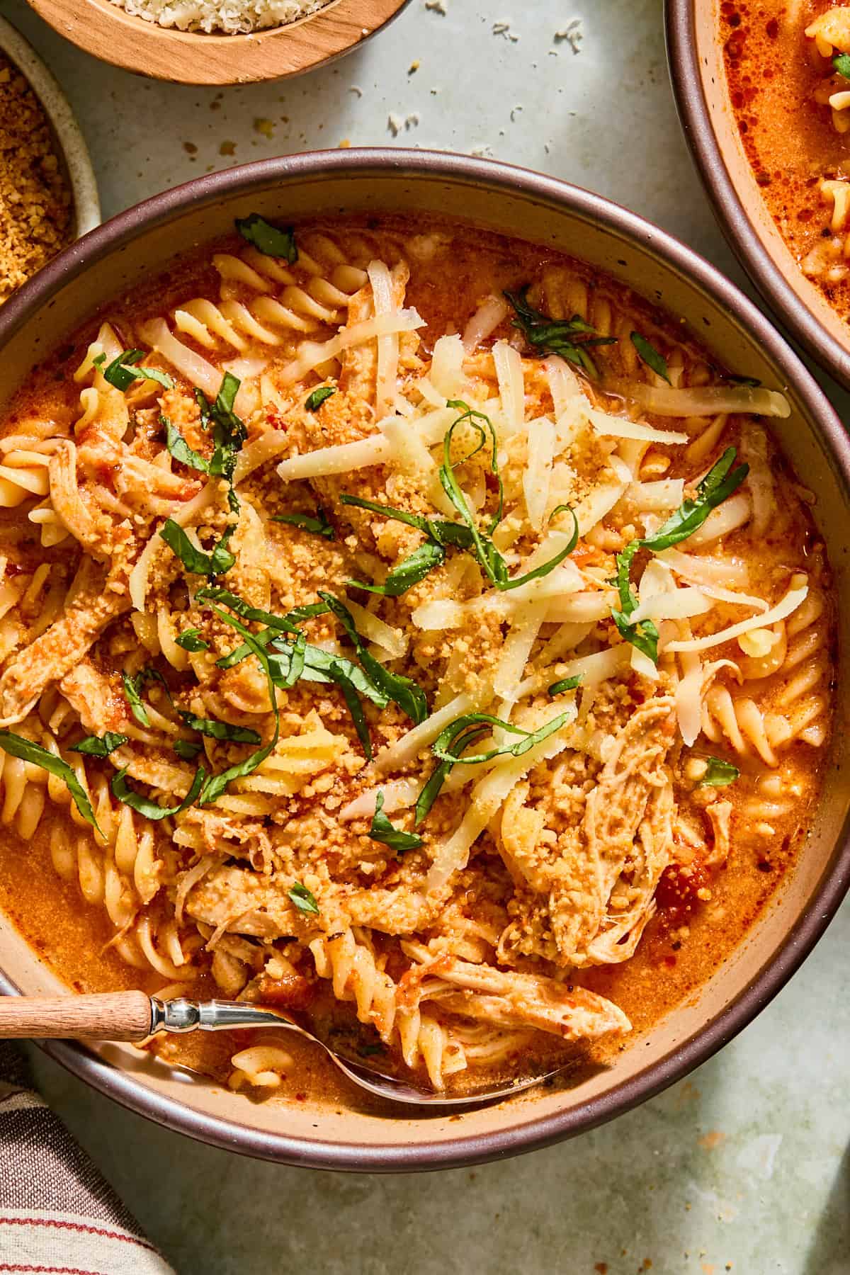 Toasted panko and shredded mozzarella being sprinkled over a bowl of chicken parmesan soup