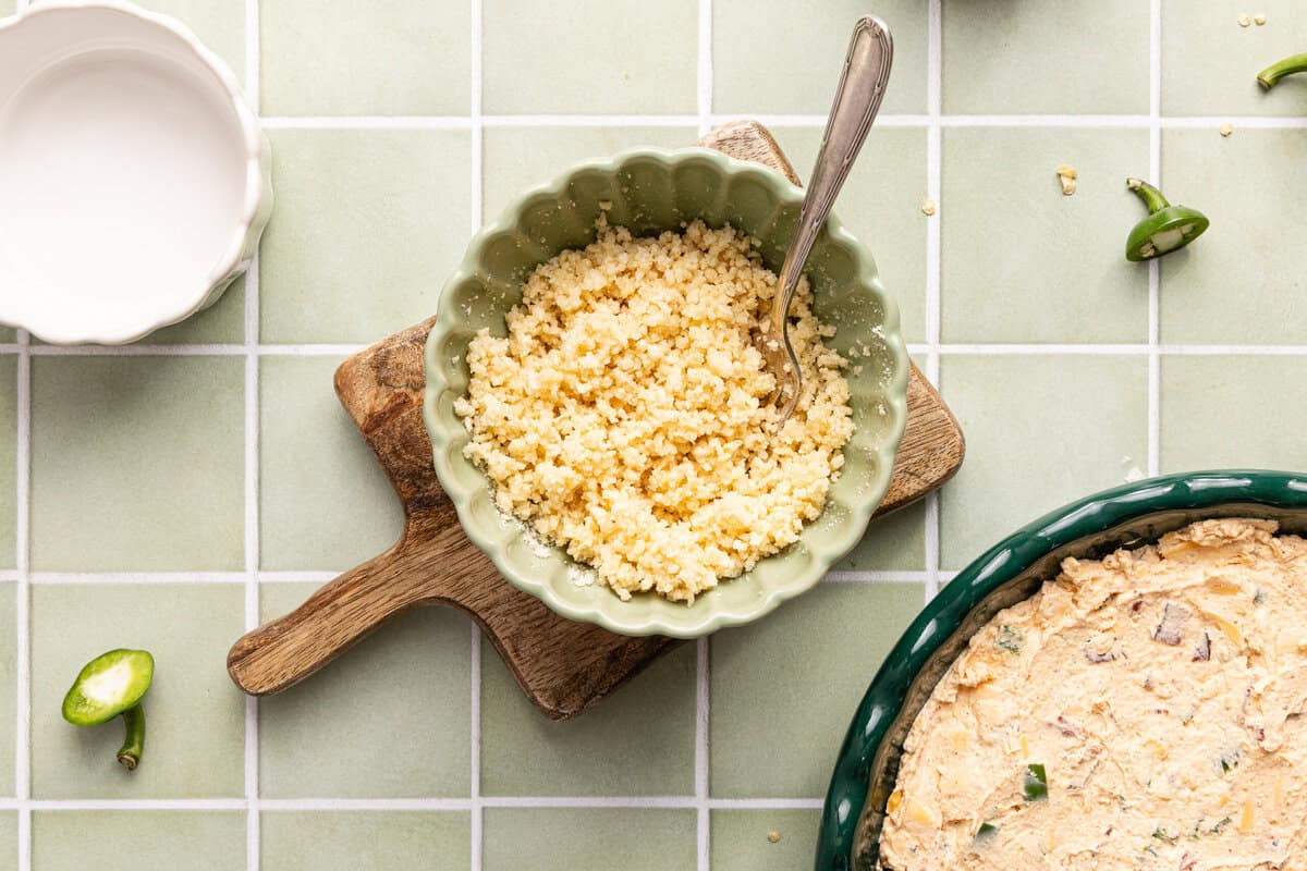 A bowl of panko mixed with butter in a green bowl with a fork.