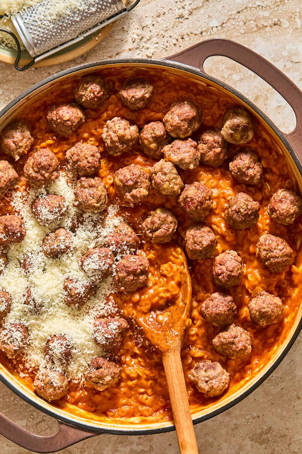 Mini meatballs and parmesan cheese atop the pan of gluten-free spaghettiOs.