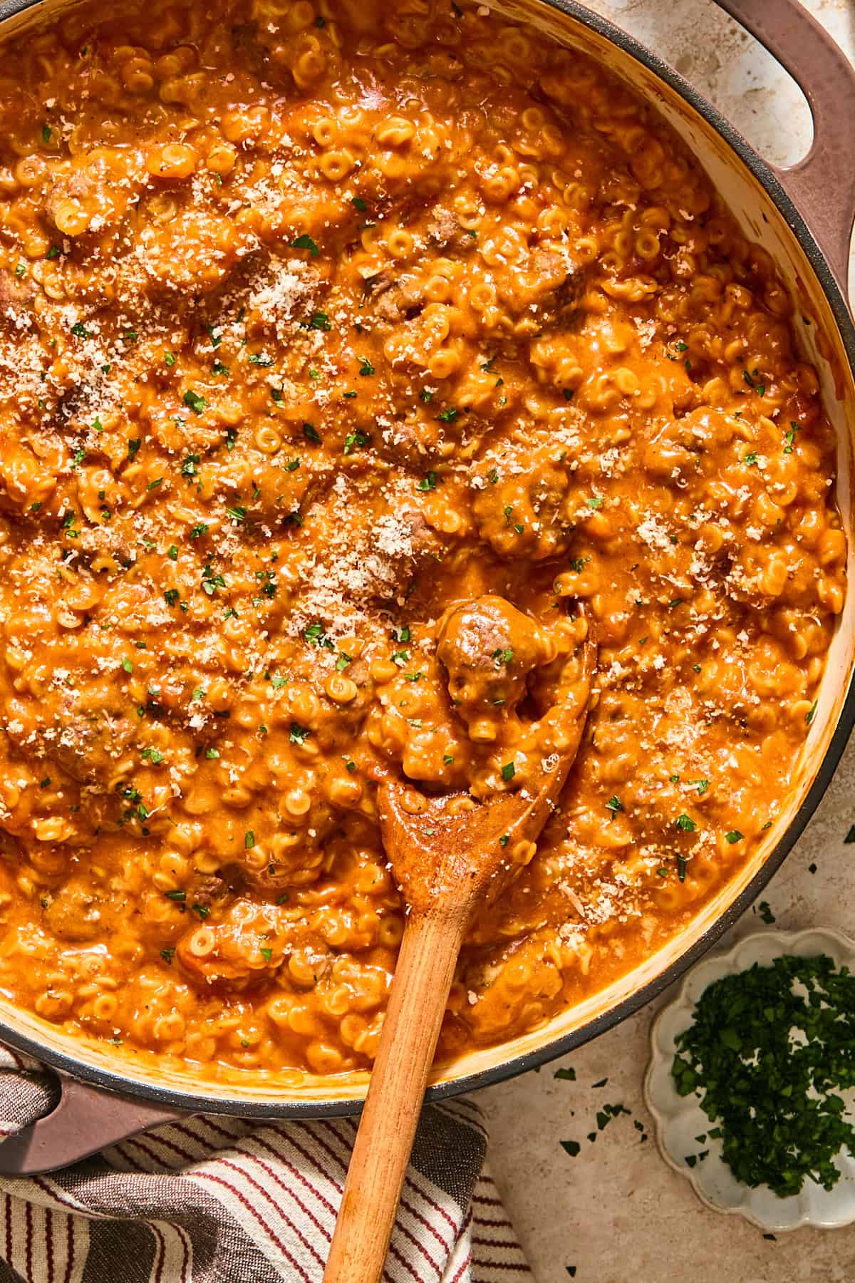 Gluten-free SpaghettiOs and mini meatballs in a pan topped with parsley and parmesan cheese.