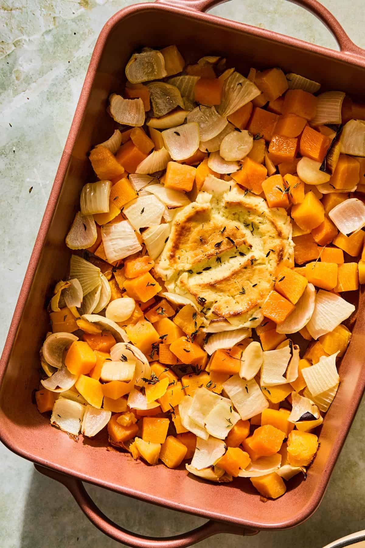 The veggies, boursin, and herbs in a baking dish after roasting in the oven.