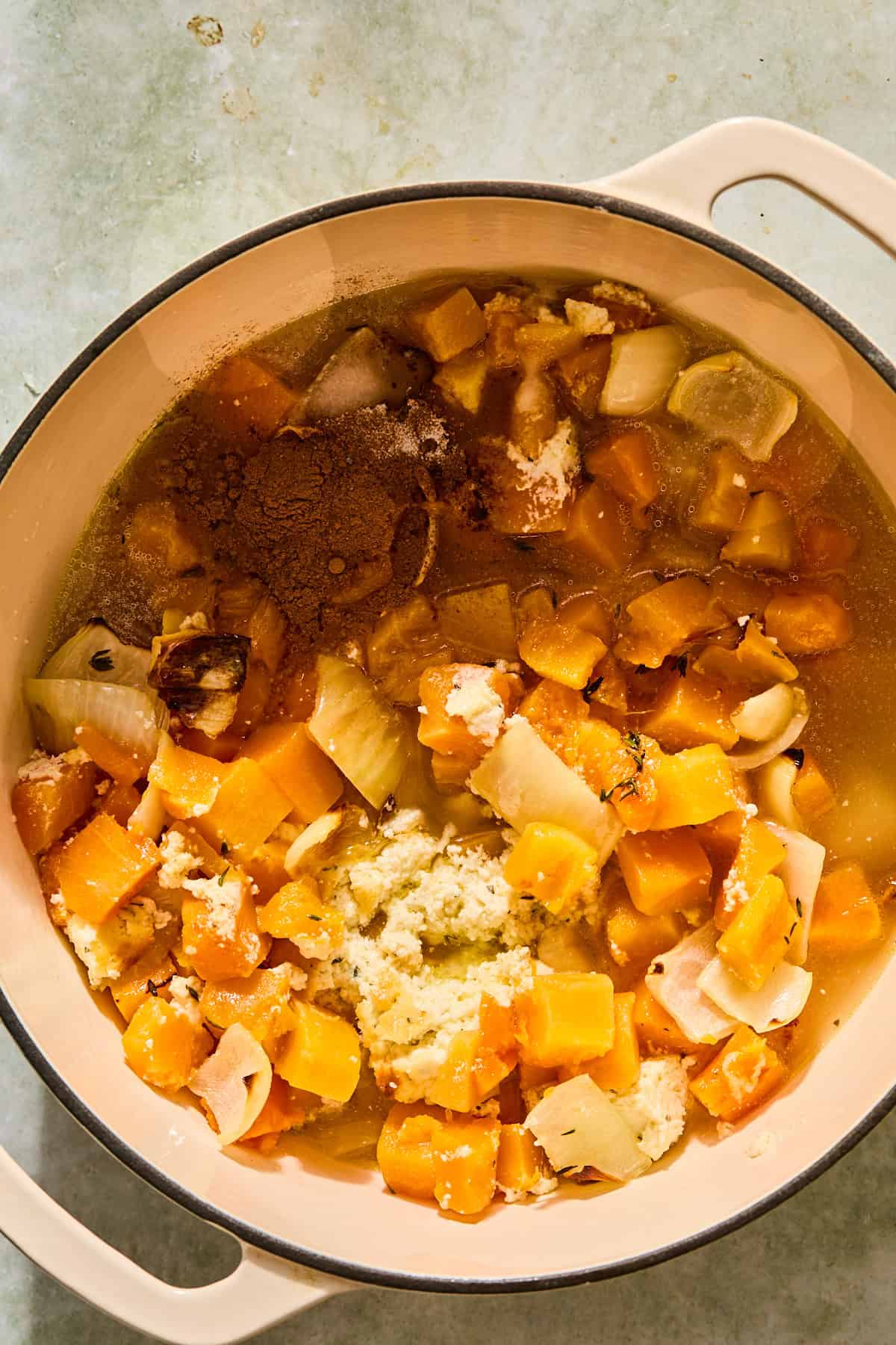 A pot filled with the roasted butternut squash ingredients before blending with an immersion blender.