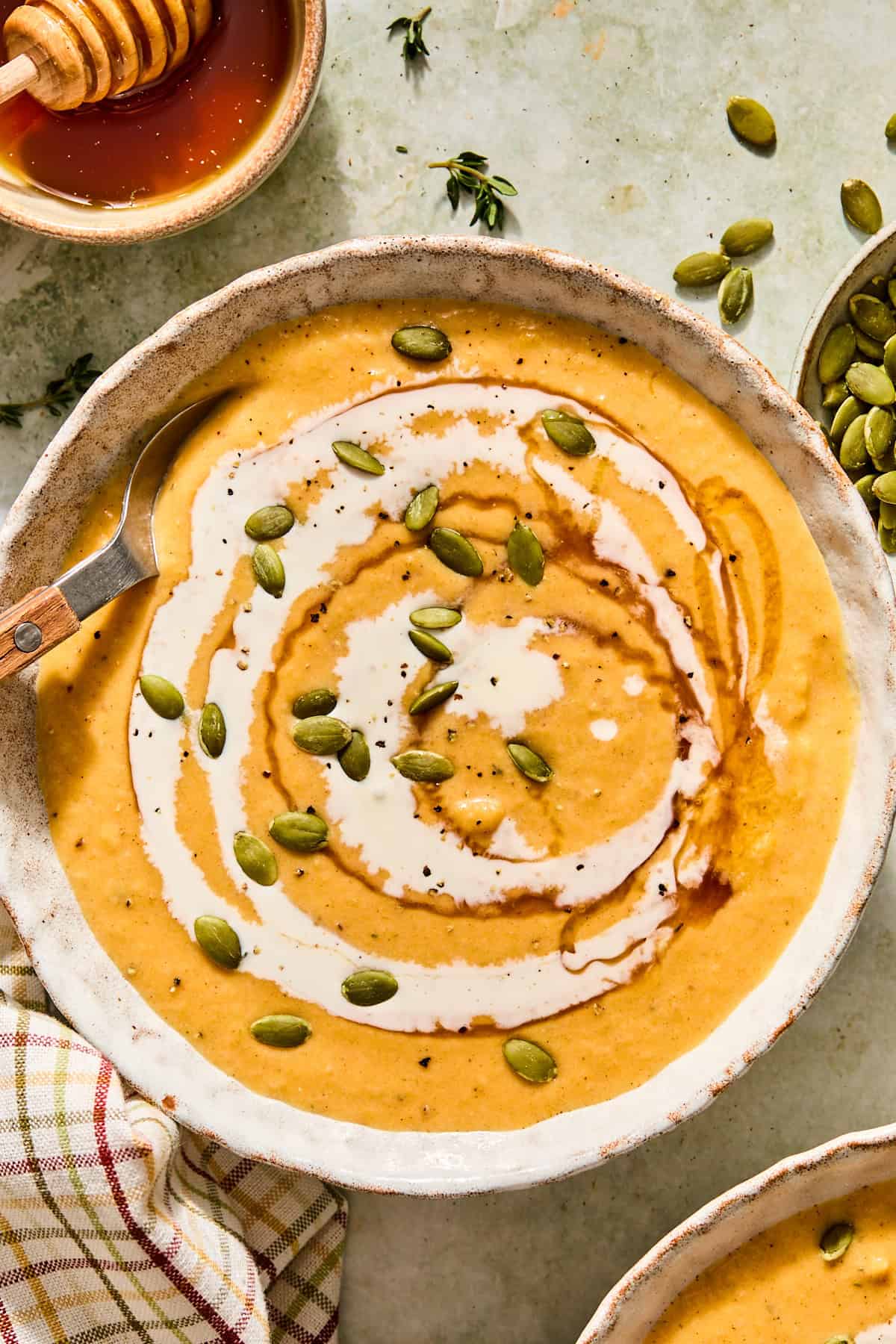Roasted butternut squash soup in a bowl topped with pumpkin seeds and a drizzle of cream.