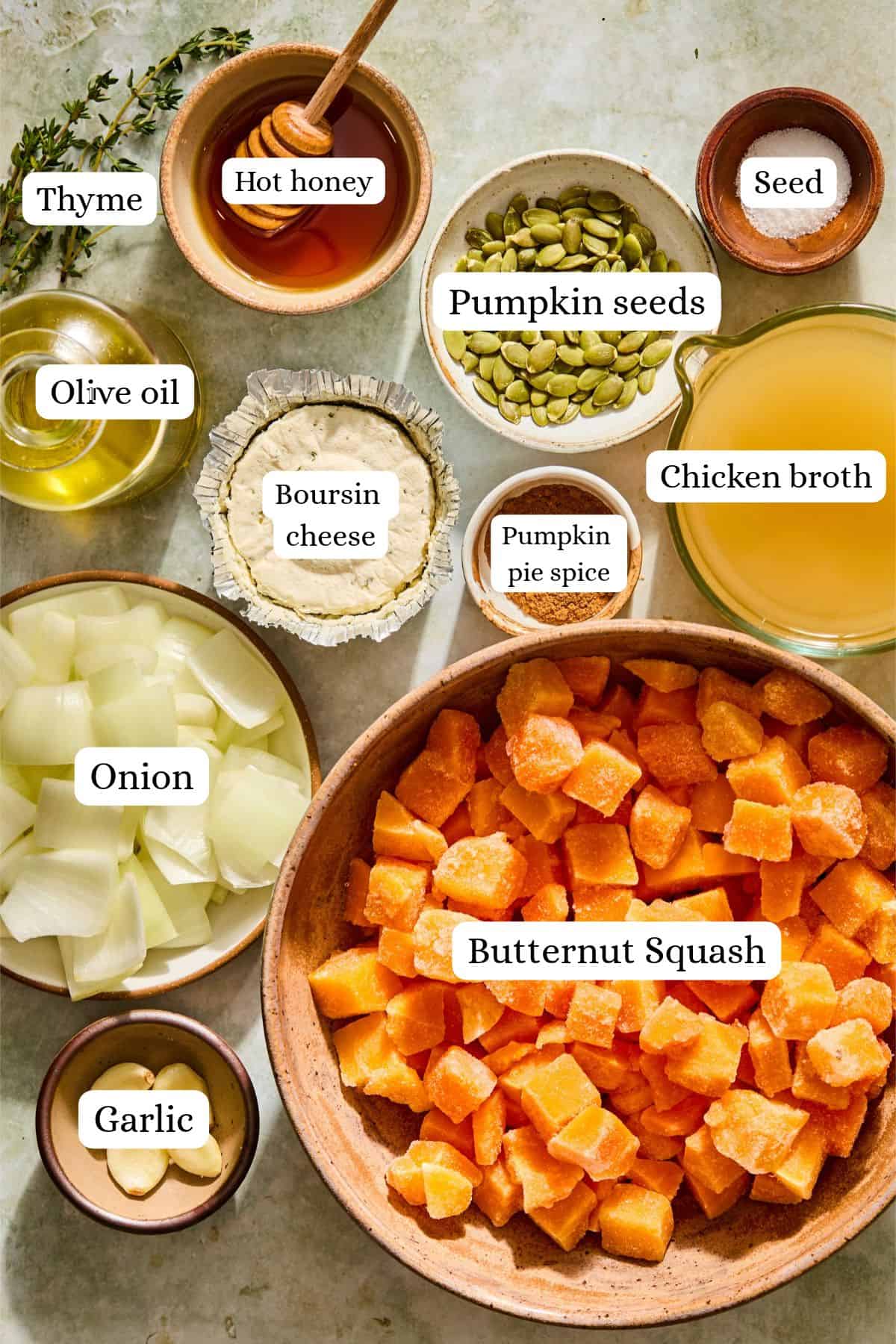 Flat lay of butternut squash soup with boursin ingredients labeled on a counter top.