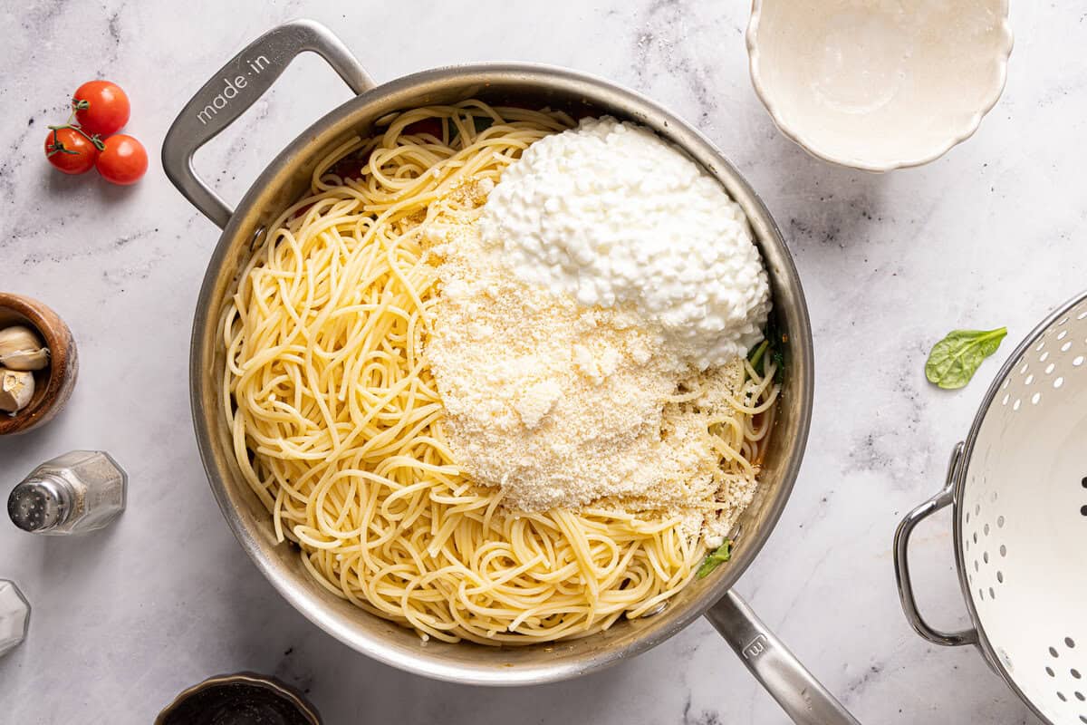 cooked spaghetti, cottage cheese, and parmesan cheese in a pot before tossing.