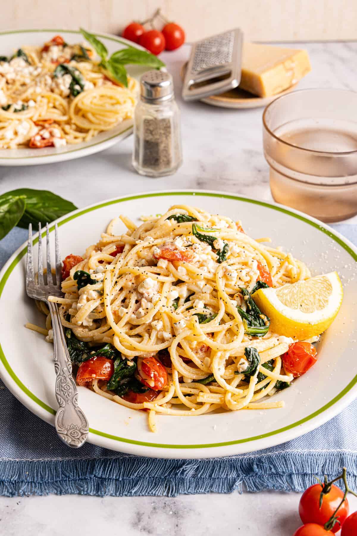 A close up of a plate filled with cottage cheese pasta with a fork and a lemon wheel.