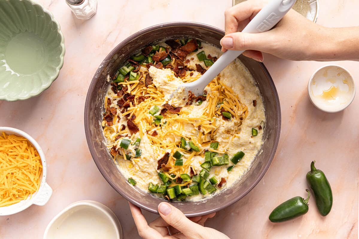 Folding in the cheese, bacon, and jalapeño to the mixing bowl with the batter.