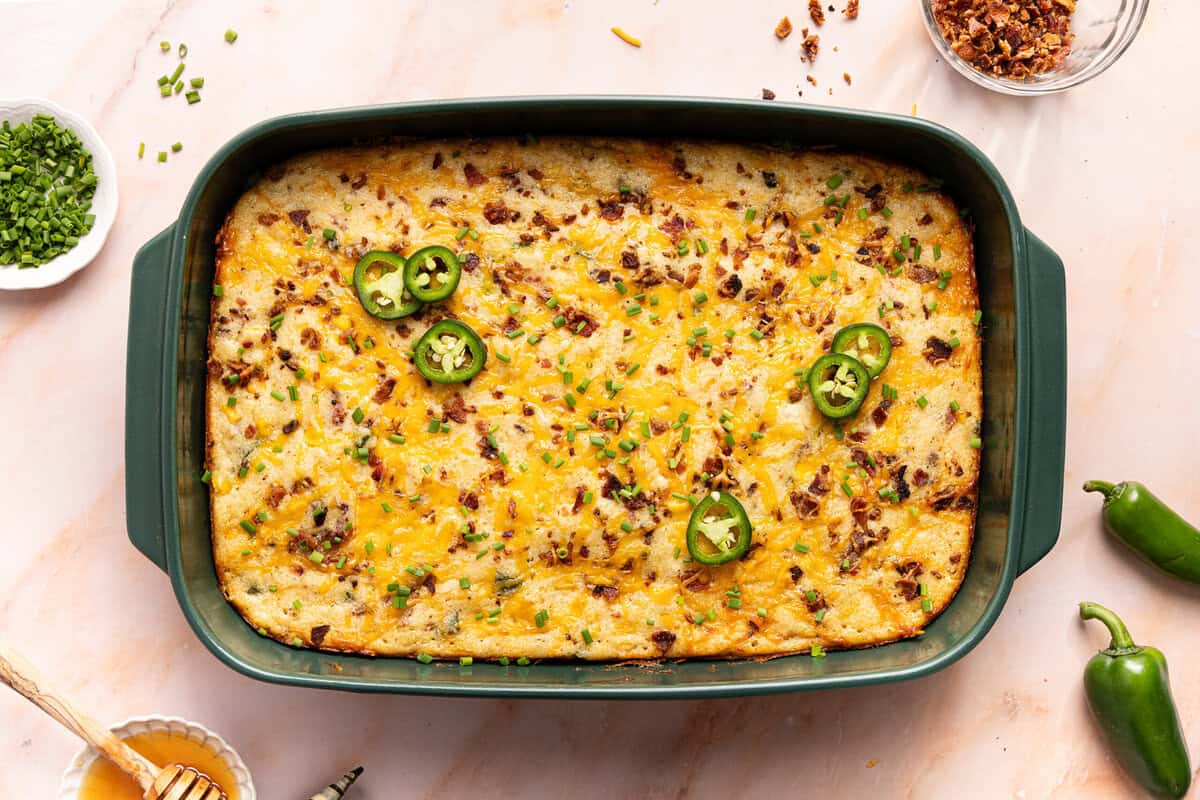 The gluten-free cornbread casserole cooling in a the green dish before slicing and serving.
