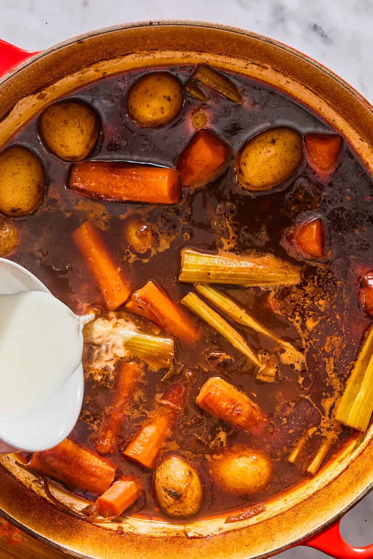 Pouring in the arrowroot slurry to the Dutch oven pot roast to thicken the gravy.