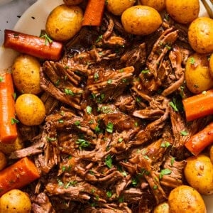 dutch oven pot roast shredded on a platter with potatoes and carrots