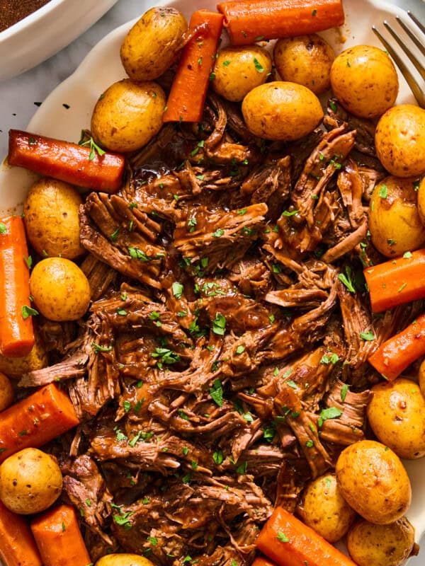 dutch oven pot roast shredded on a platter with potatoes and carrots