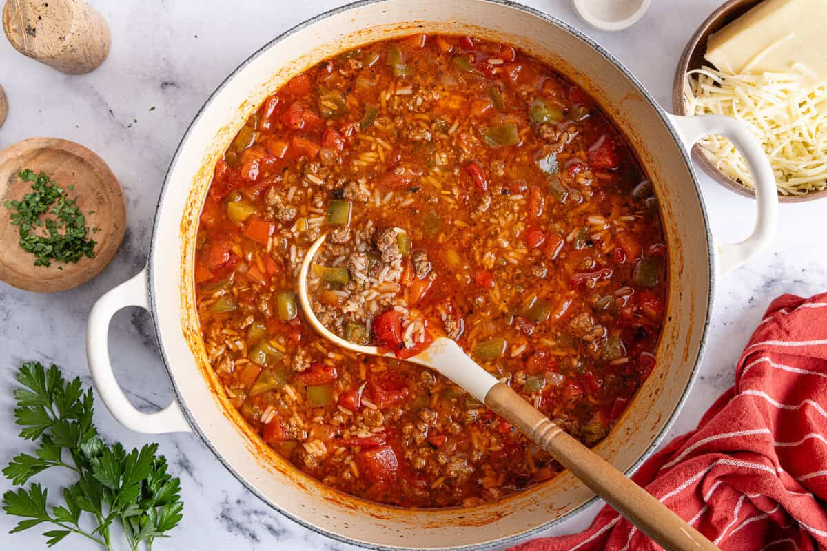 simmering stuffed pepper soup in a soup pot with a ladle resting inside.