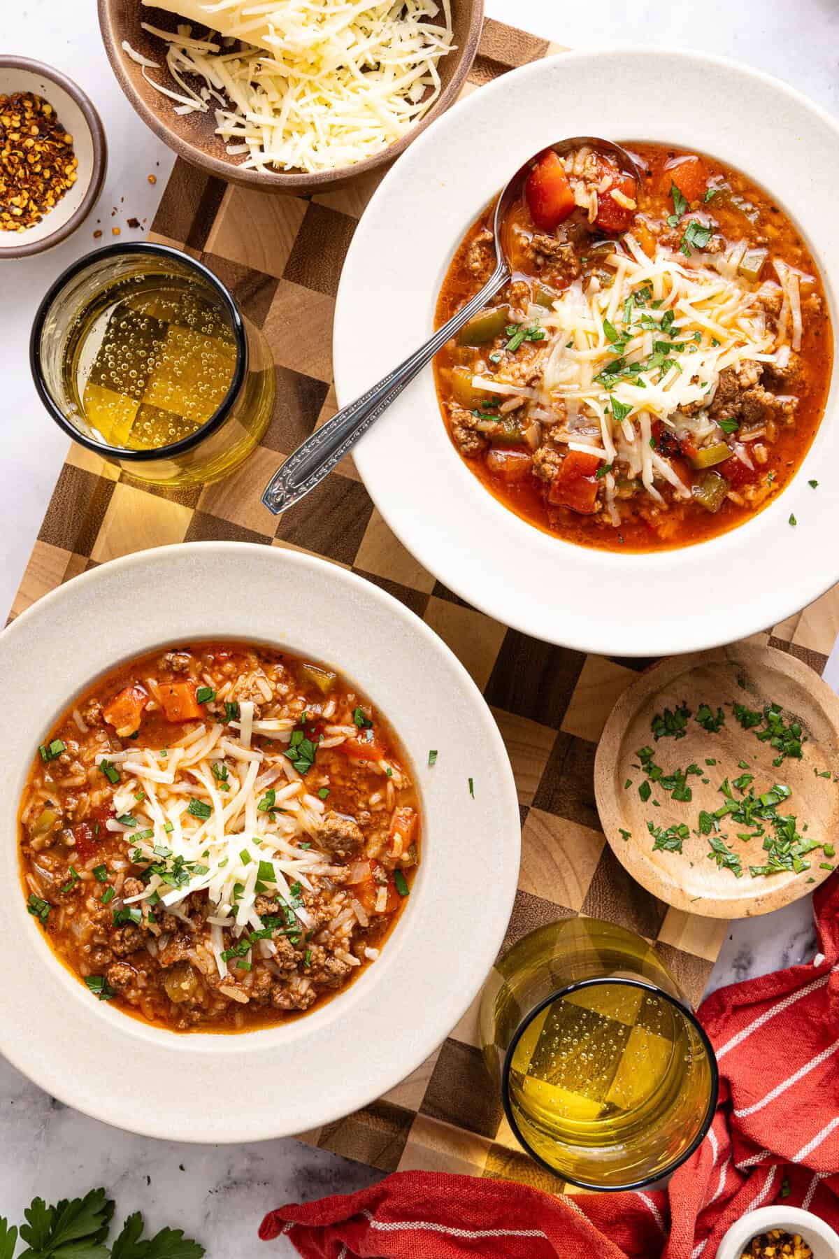 an overhead shot of two bowls filled with gluten-free stuffed pepper soup topped with shredded cheese and cilantro.