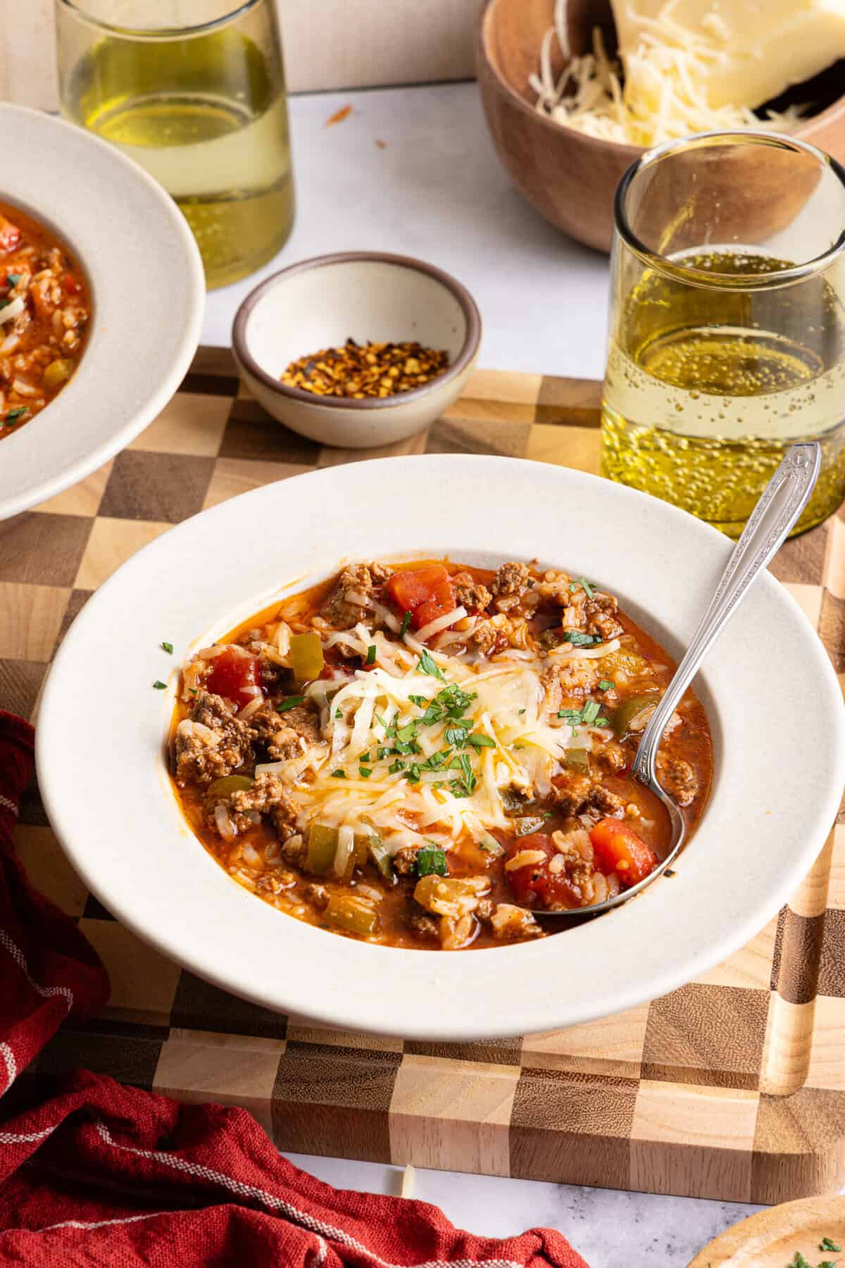 A white bowl with stuffed pepper soup and a silver spoon resting on the side. 